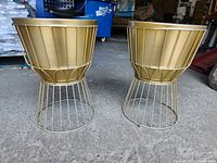 Front view of two gold-colored planters mounted on wire stand bases, showing full form and structure.