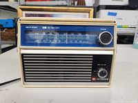 Front view showing tuning dial, tuning and volume knobs, speaker grill and Hitachi branding.