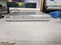 Front view of silver Koss DVD player, disc tray closed, power indicator on
