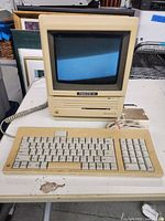 Front view of Macintosh SE desktop computer powering on with keyboard in front
