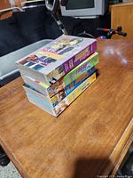 Stack of twelve High School Debut manga books on a wooden surface, showing the side spines with volume numbers.