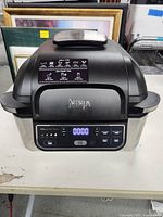 Front view of Ninja Foodi Grill showing the lid with control panel on the front base.