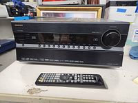 Front view of Onkyo TX-NR609 AV receiver with remote placed in front on a white table.
