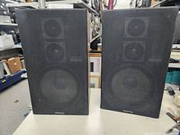 Pair of black rectangular Sanyo speakers with cloth front covers, placed side by side.