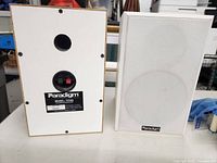 Front and rear views of one Paradigm Titan speaker pair - white rectangle speakers with fabric grille and rear connection terminals.