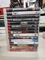 Stack of 15 PS3 game cases showing titles and spine details
