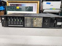 Front view of Sanyo stereo integrated amplifier showing sliders, display, and damaged plastic cover.