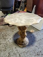 Side table viewed from an angle showing carved pedestal and structural form.