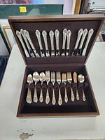Full view of the silver plated flatware set in wooden box, showing layout of forks, spoons, and knives with floral pattern