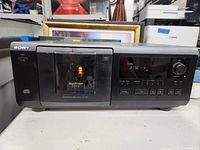 Front view showing Sony branding, power button, digital display with text reading 'disc - 9', load/eject button, and control buttons.