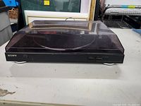 Front view of Sony turntable system with closed dust cover, showing model and controls on front panel.