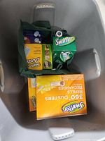 Photo showing various boxed Swiffer cleaning accessory refills inside a green tote.
