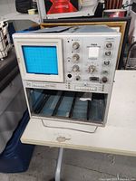 Front view of Tektronix 7904 oscilloscope showing CRT screen, control knobs, and empty module slots below.