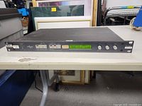 Front view of XTA Electronics DP-200 audio processor on a table showing buttons, knobs, and LCD screen.