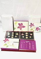 Four presentation cases standing and two opened trays showing coins.