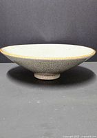 Side view of footed porcelain bowl with crackle glaze on black background