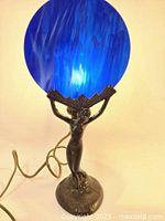 Front view of assembled lamp with blue glass shade showing bronze female figure base