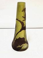 Front view of yellow-green vase with brown floral vines wrapping around body showing narrow neck widening at base.