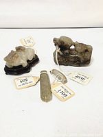 Four carvings grouped: frog figurine, mythical creature, tube pendant and carved cylinder