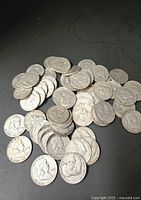Pile of circulated silver half dollars on dark surface