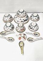 Photo shows seven porcelain bowls and three spoons, all decorated with dragons and traditional patterns in multi-color enamels.