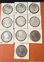 Ten coins in cardboard flips arranged in grid.