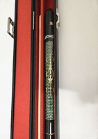 Close-up of pool cue showing black body with green dotted pattern and yellow design.