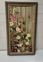 Full view of framed painting showing hollyhocks against wood fence with rustic frame