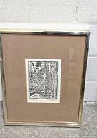 Framed black and white lithograph featuring forest scene with trees and water, gold-toned frame and neutral brown matte shown