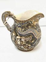 Front and side view of Japanese Satsuma style ceramic pitcher depicting Seven Lucky Gods and raised enamel dots.