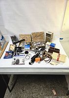 Complete overview of the vintage camera equipment lot including lenses, flash, cases, and boxes on a table.