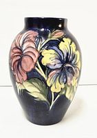 Front view of the cobalt blue vase with intricate floral tubelined design including large flowers and leaves in yellow, pink, purple, and green.