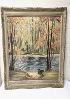 Full view of framed painting showing colorful autumn landscape with river, boat, and trees.
