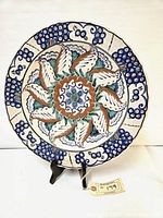 Front view of the Icaros Rhodes pottery plate showing detailed colorful floral and geometric patterns in cobalt blue, orange, green, and white.
