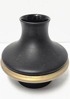 Side view showing the matte black exterior, broad round base narrowing to a slim neck, and gold trim band around widest center.