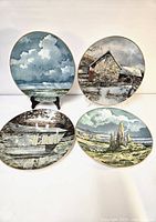 Four Royal Doulton decorative plates with different scenic designs displayed on stands and flat, showing overall lot.