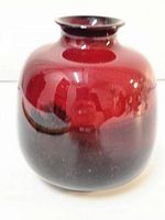 Front view of red and black flambe glazed Royal Doulton vase, showing rounded form and glossy surface.