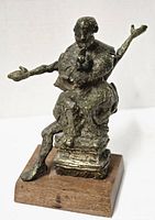 Front angled view of bronze sculpture showing seated figure and wooden base.