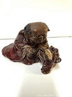 Front and side view of ceramic figurine of an elderly man with a tiger, detailed face and robe glaze.