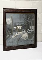 Framed winter landscape painting leaning against white wall showing entire artwork and frame.
