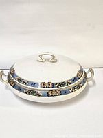 Oval tureen with lid closed showing decorative band around the edges and handles on both sides and lid