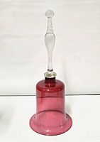 Full view of Victorian cranberry glass bell showing cranberry bell body and clear handle with clapper inside