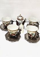 Full lot showing one porcelain teapot centered among four porcelain cups each on an octagonal metal saucer with dragon handle