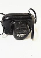 Front view of black leather carrying case with Canon QL embossed, showing surface wear and strap