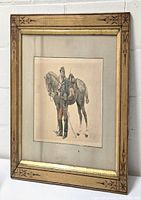 Framed watercolor artwork showing soldier and horse, with the frame decorated in geometric star patterns and gold inner edge, presented leaning against a white surface.