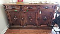 Full front view of the antique sideboard showing the three carved panel doors and three drawers above.
