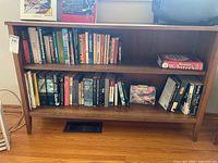 Front view of brown wooden bookcase with books on shelves
