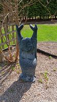 Full view of Happy Buddha statue standing outdoors on gravel with arms raised, showing overall shape and size.