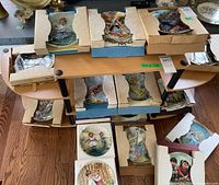 Shelf filled with boxed and unboxed collectible plates, mostly featuring children in outdoor scenes. Plates are protected with cardboard and foam packaging.