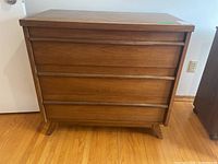 Full front view of the Gibbard wooden dresser showing three drawers and angled legs on hardwood floor.
